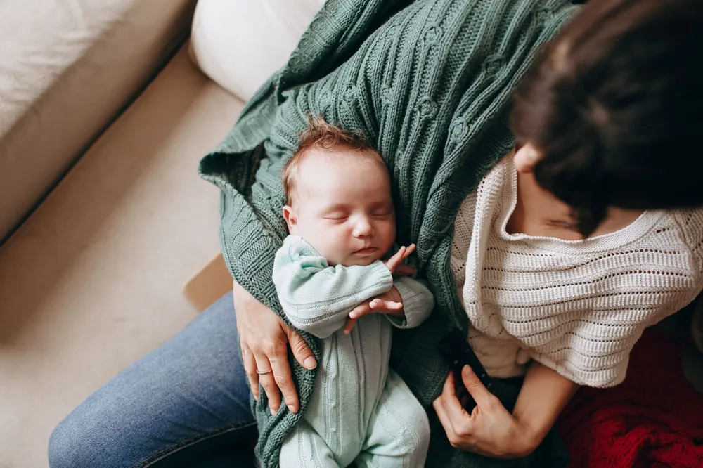 New mother holding her newborn, coping with postpartum night sweats