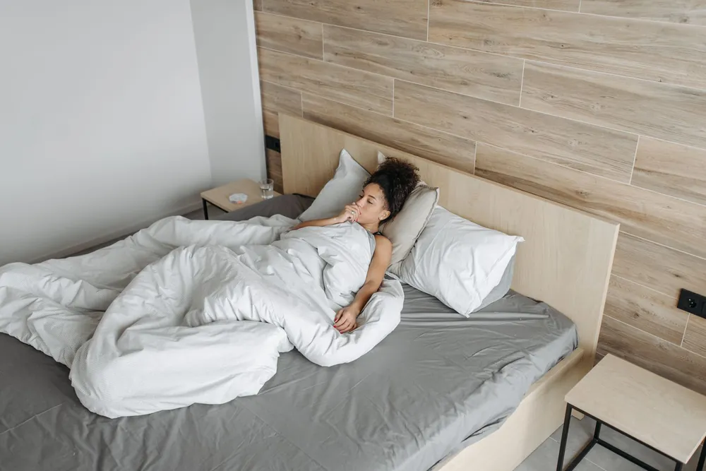 Woman under a thick duvet, sweating at night even though she's cold